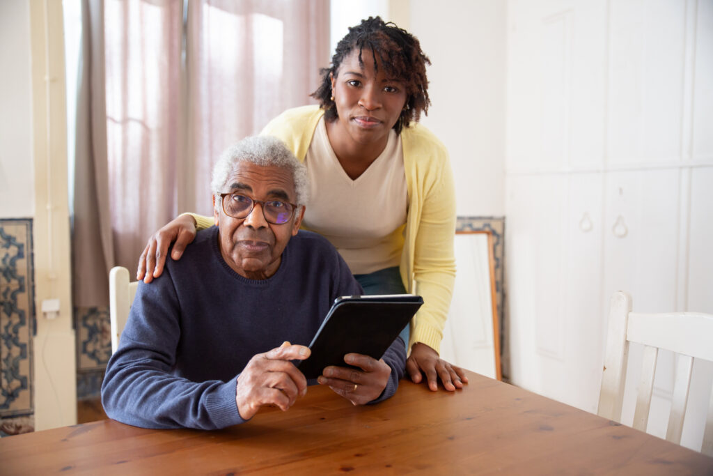 7551582-7551582 A Woman Standing Beside the Elderly Man Holding a Tablet